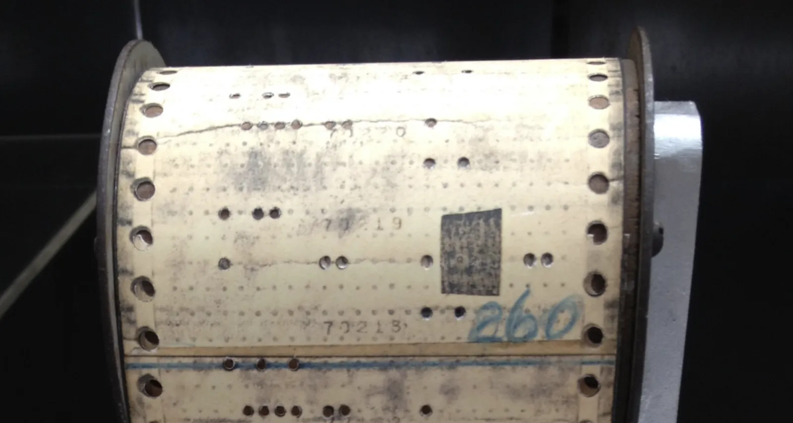 Punch card software tape with a physical patch applied over specific holes to change the program's output.